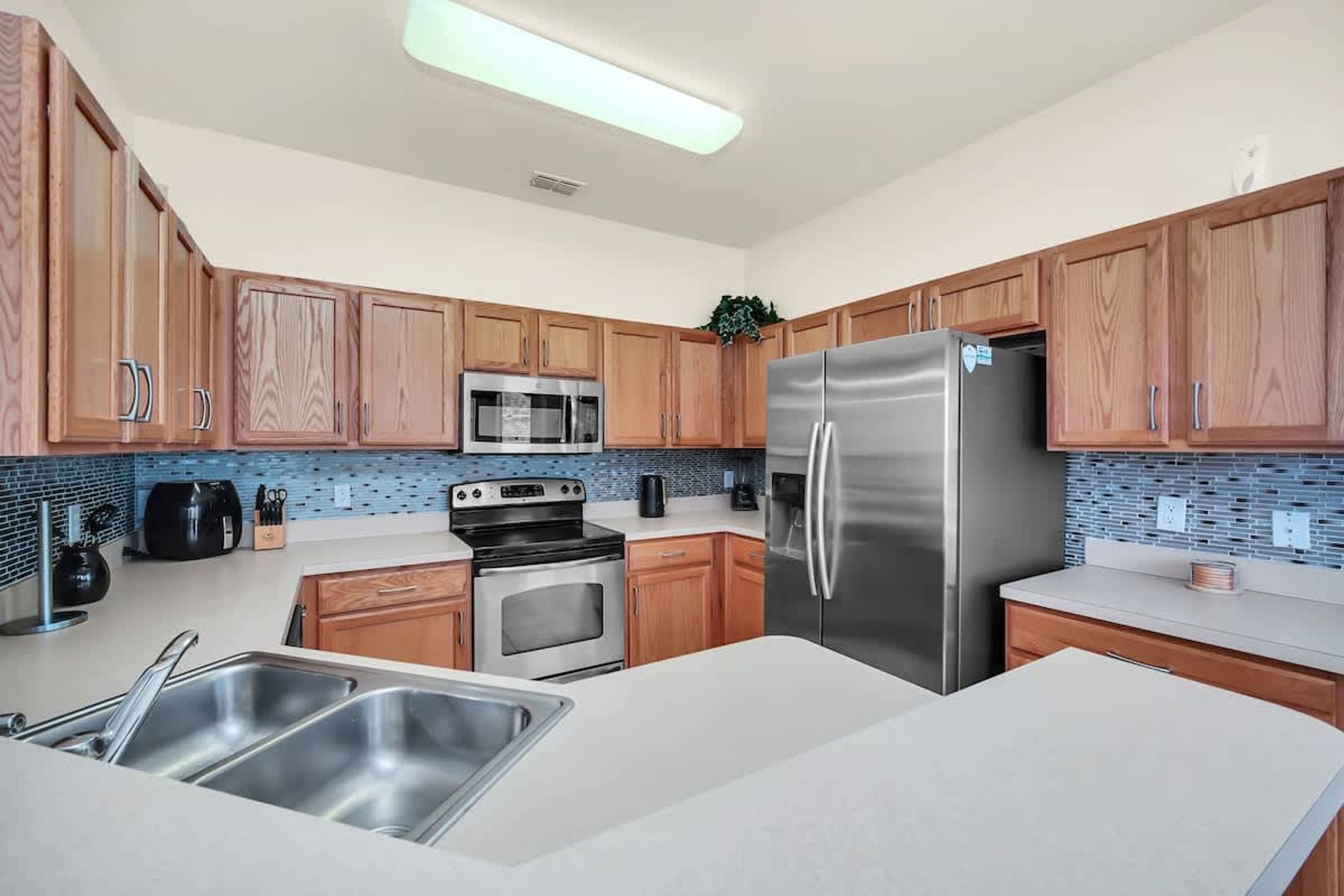 A modern kitchen with wooden cabinets, stainless steel appliances, and a tiled backsplash.