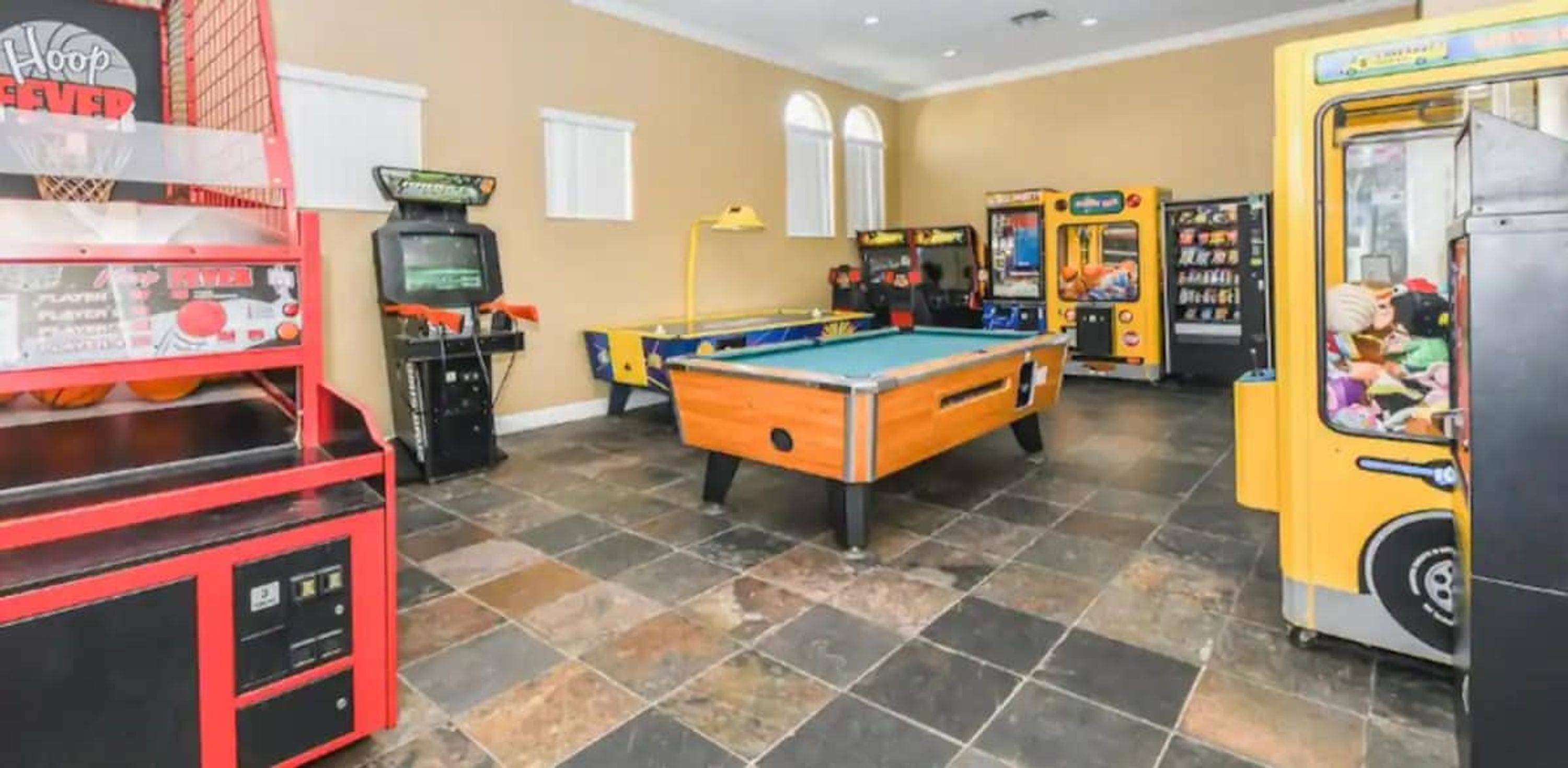 Una sala recreativa con mesa de billar, juegos de arcade y canasta.
