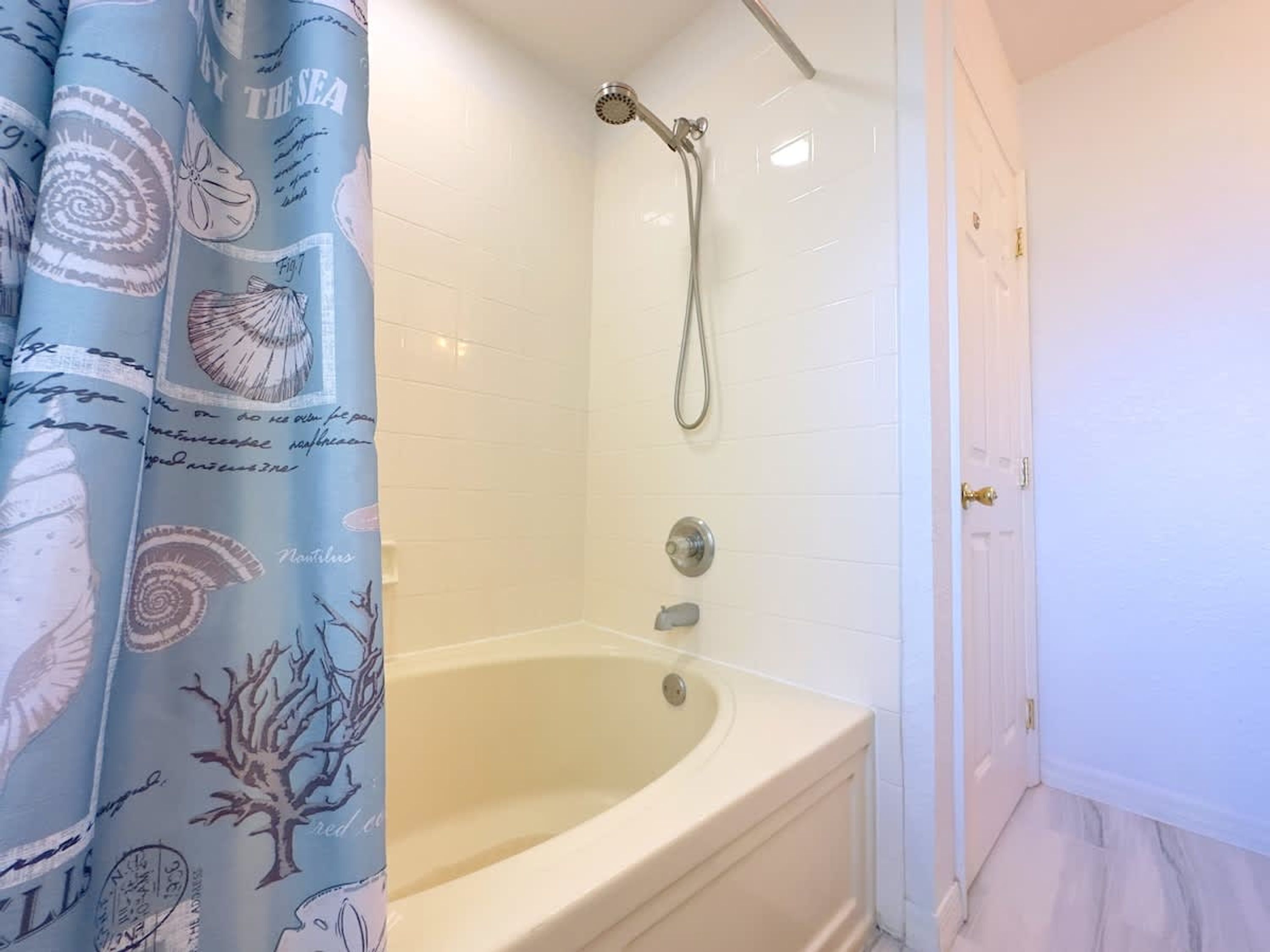 A bathroom with a bathtub, a shower, and a white door.