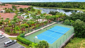 A tennis court surrounded by lush greenery and a body of water. - Very Near Disney 3 Bd Condo Walmart 1 min Away (Kissimmee)