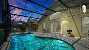 A swimming pool with a glass ceiling, lounge chairs, and a barbecue area.