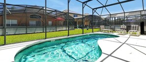 A swimming pool with a glass enclosure, surrounded by outdoor seating and a view of neighboring buildings. - Private Pool Oasis With King Bed (Kissimmee)