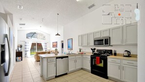 A spacious kitchen with white cabinets, a central island, and a large window.