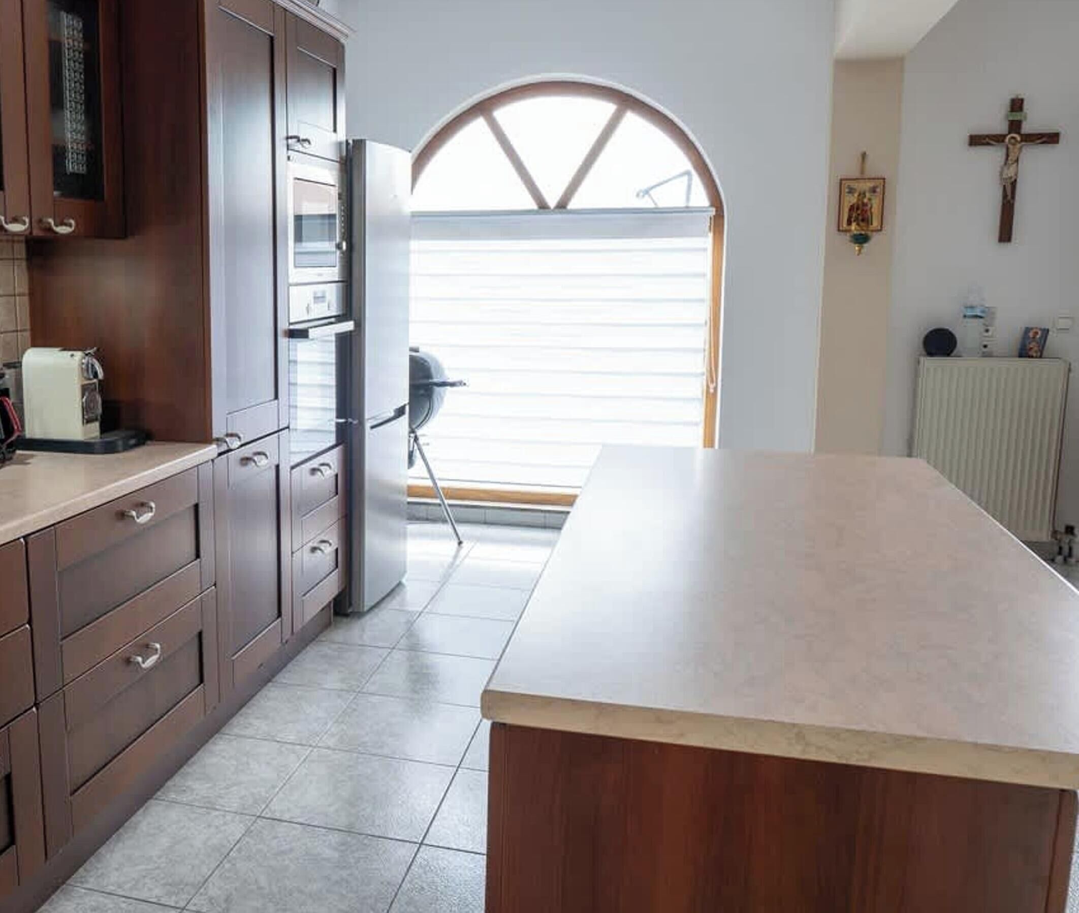 Una cocina con armarios de madera, una encimera y un ventanal grande.