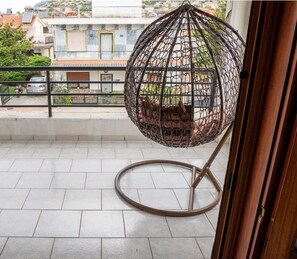 A balcony with a hanging chair, a view of the neighborhood, and a tiled floor. - Great Villa Philipi in Krinides (Kavala)
