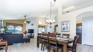 A spacious living area with a dining table, chairs, a sofa, and a TV. - 4bd Villa With Solar Heated Pool Near Disney No Resort Fee (Davenport)