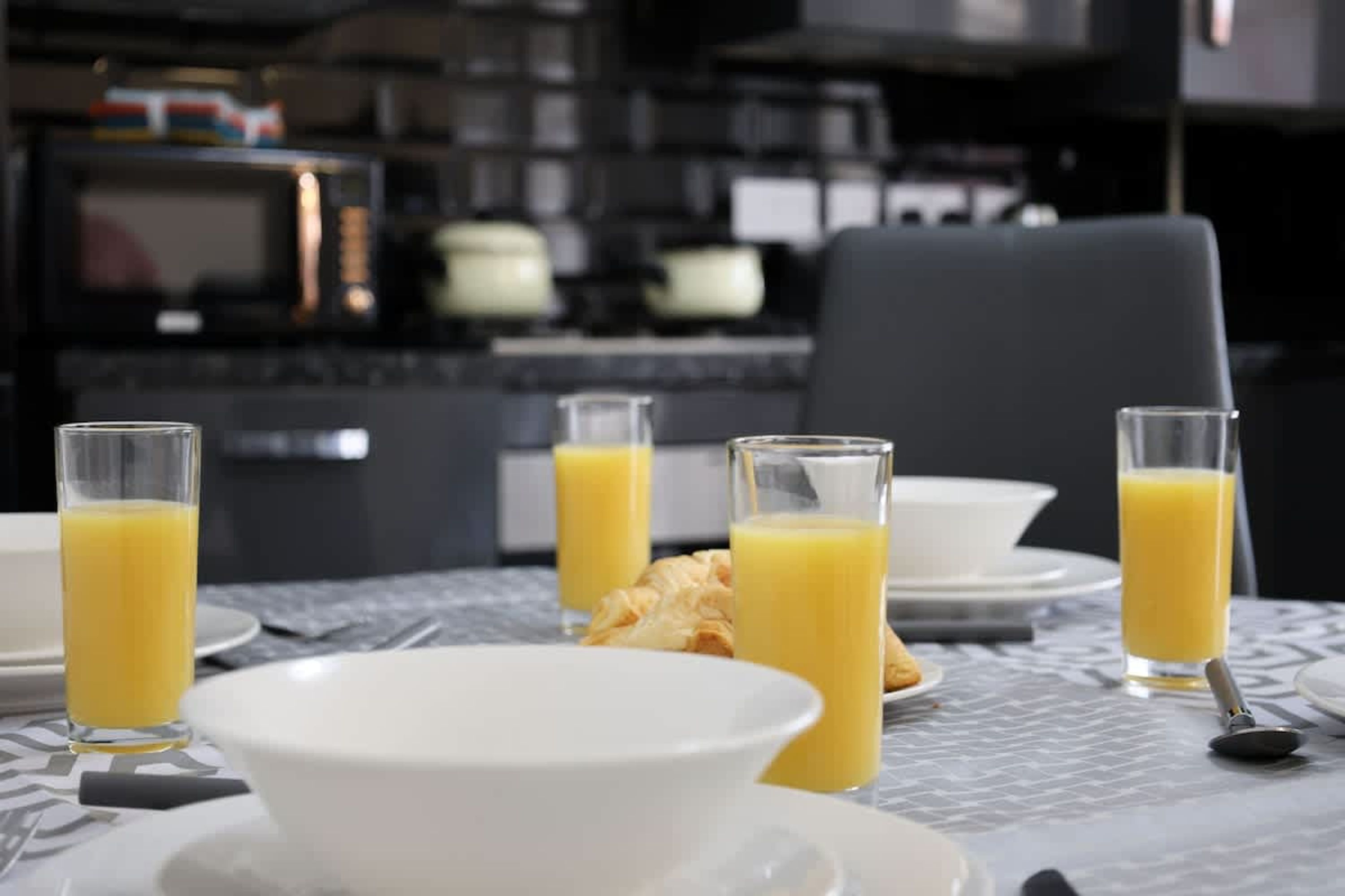 Een ontbijtsetting met een tafel voor twee personen, compleet met borden, kommen en glazen jus d'orange.