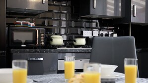 Ett modernt kök med svarta skåp, en mikrovågsugn, en spis och ett matbord med tallrikar och glas fyllda med apelsinjuice.