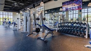 Een sportschool met diverse fitnessapparaten, waaronder krachtapparaten en gewichten.