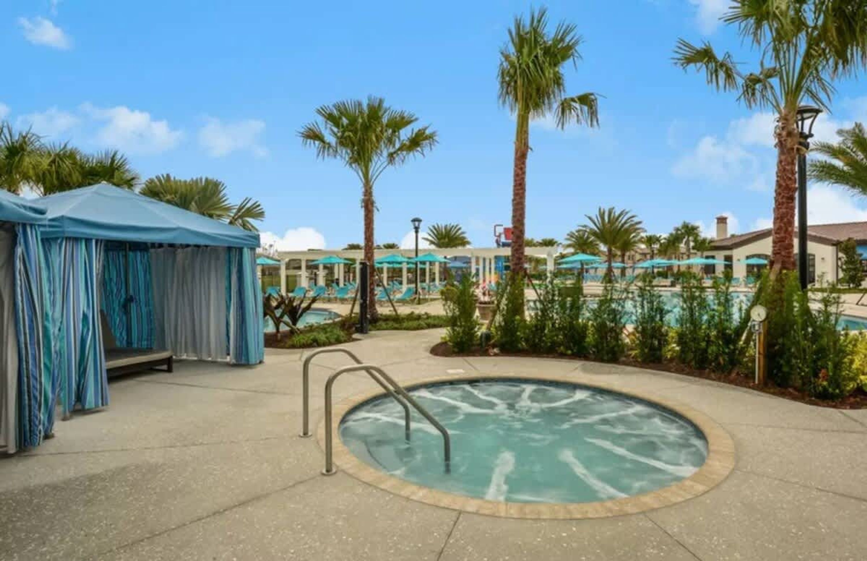 A pool area with a hot tub, lounge chairs, and palm trees.