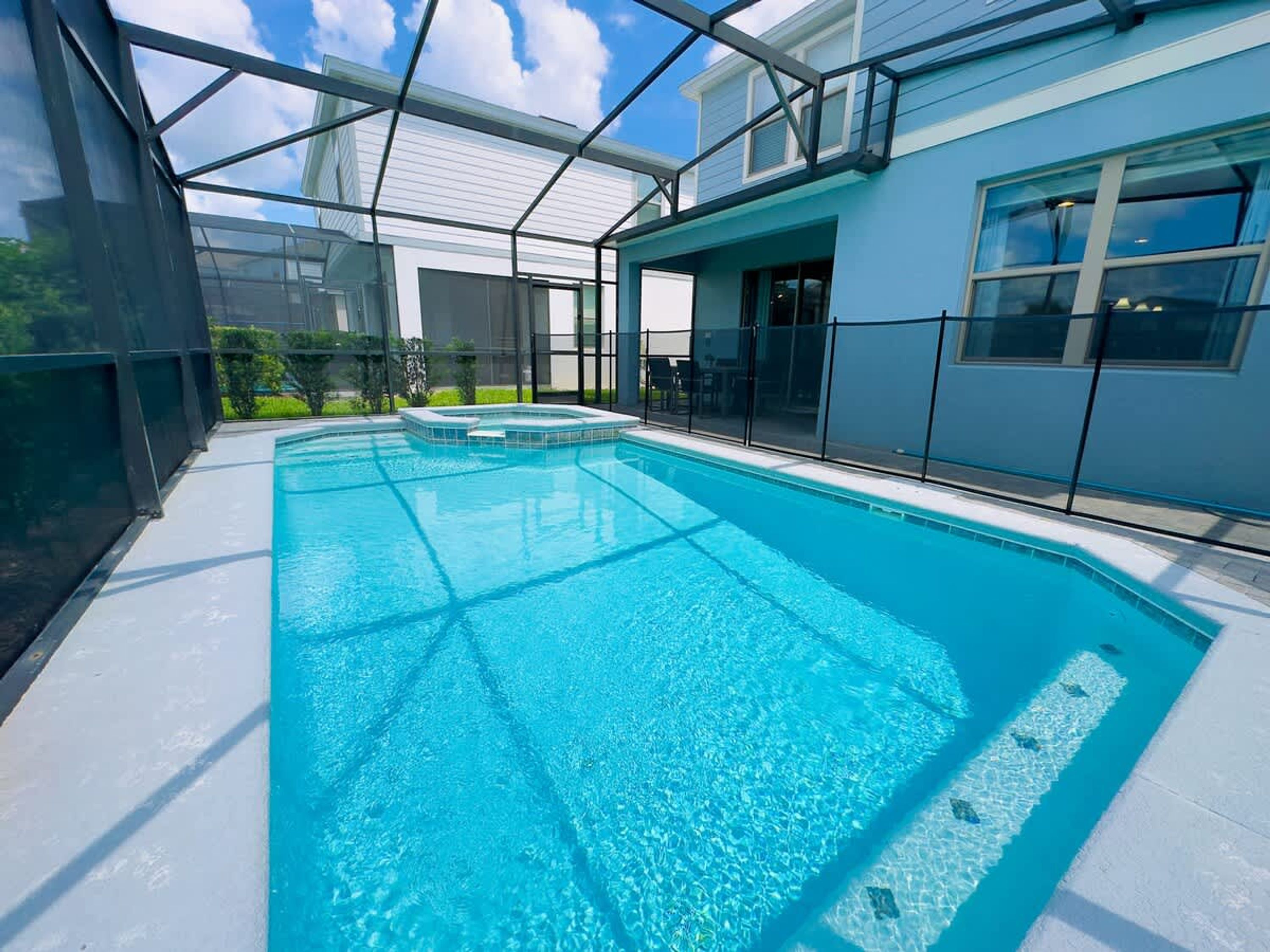 A swimming pool with a glass enclosure, surrounded by a modern building with large windows.