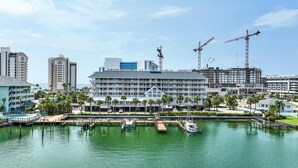 A waterfront hotel with multiple balconies, a marina with boats, and construction cranes in the background. - 445 Clearwater Hamden (Clearwater Beach)