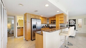 A modern kitchen with wooden cabinets, stainless steel appliances, and a granite countertop. - 445 Clearwater Hamden (Clearwater Beach)