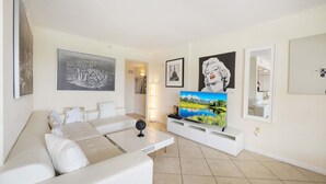 A modern living room with a white sofa, a flat-screen TV, and artwork on the walls. - 445 Clearwater Hamden (Clearwater Beach)