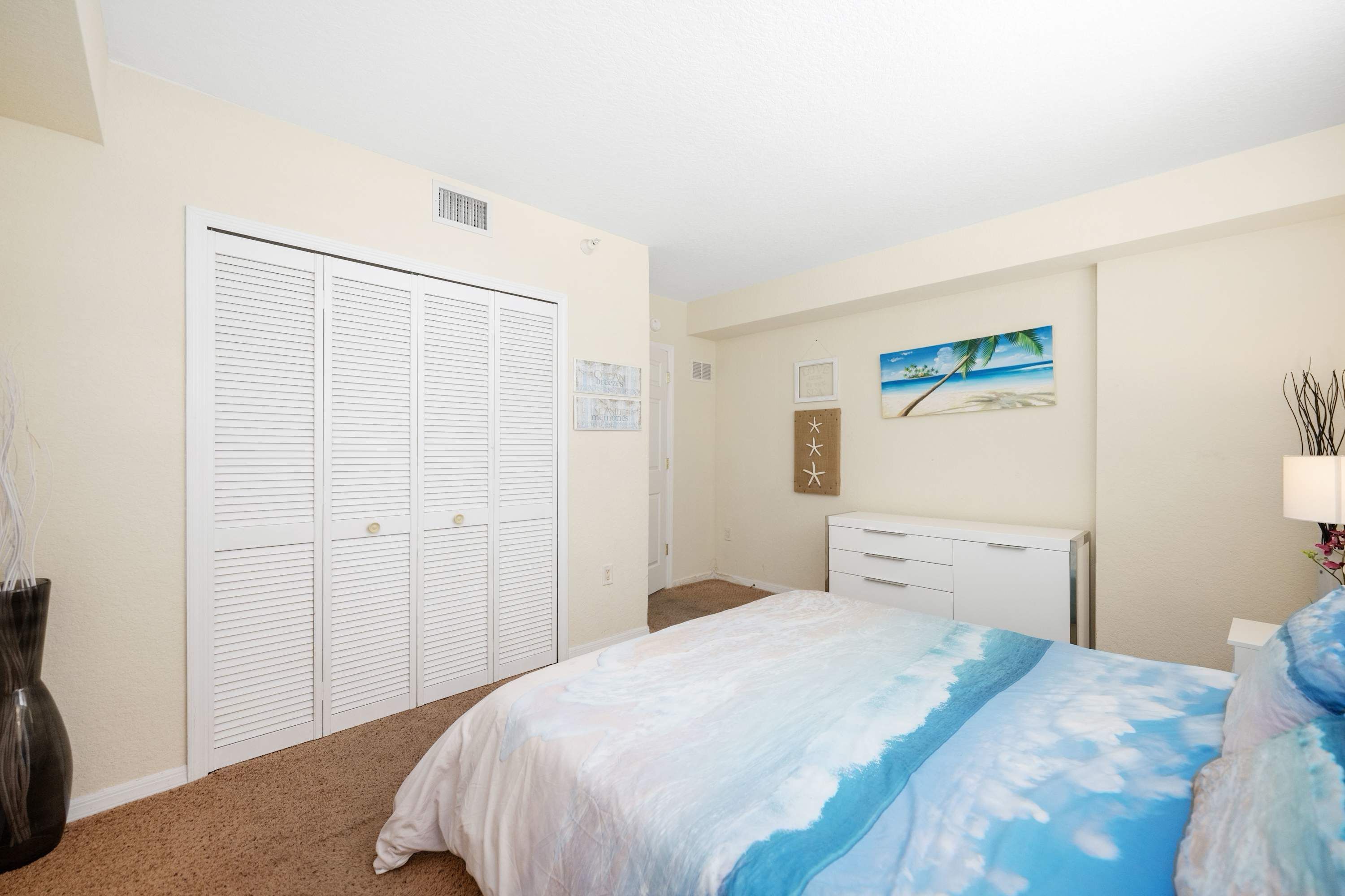 A bedroom with a bed, a closet, a dresser, and a painting on the wall.