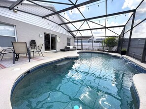A swimming pool with a glass enclosure, a covered patio area, and outdoor furniture. - Less Than 10 Minutes From Disney 3Bd Villa With Pool (Kissimmee)