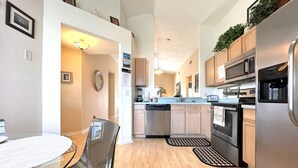 Una cucina moderna con elettrodomestici in acciaio inossidabile, mobili in legno e un tavolo da pranzo in vetro.