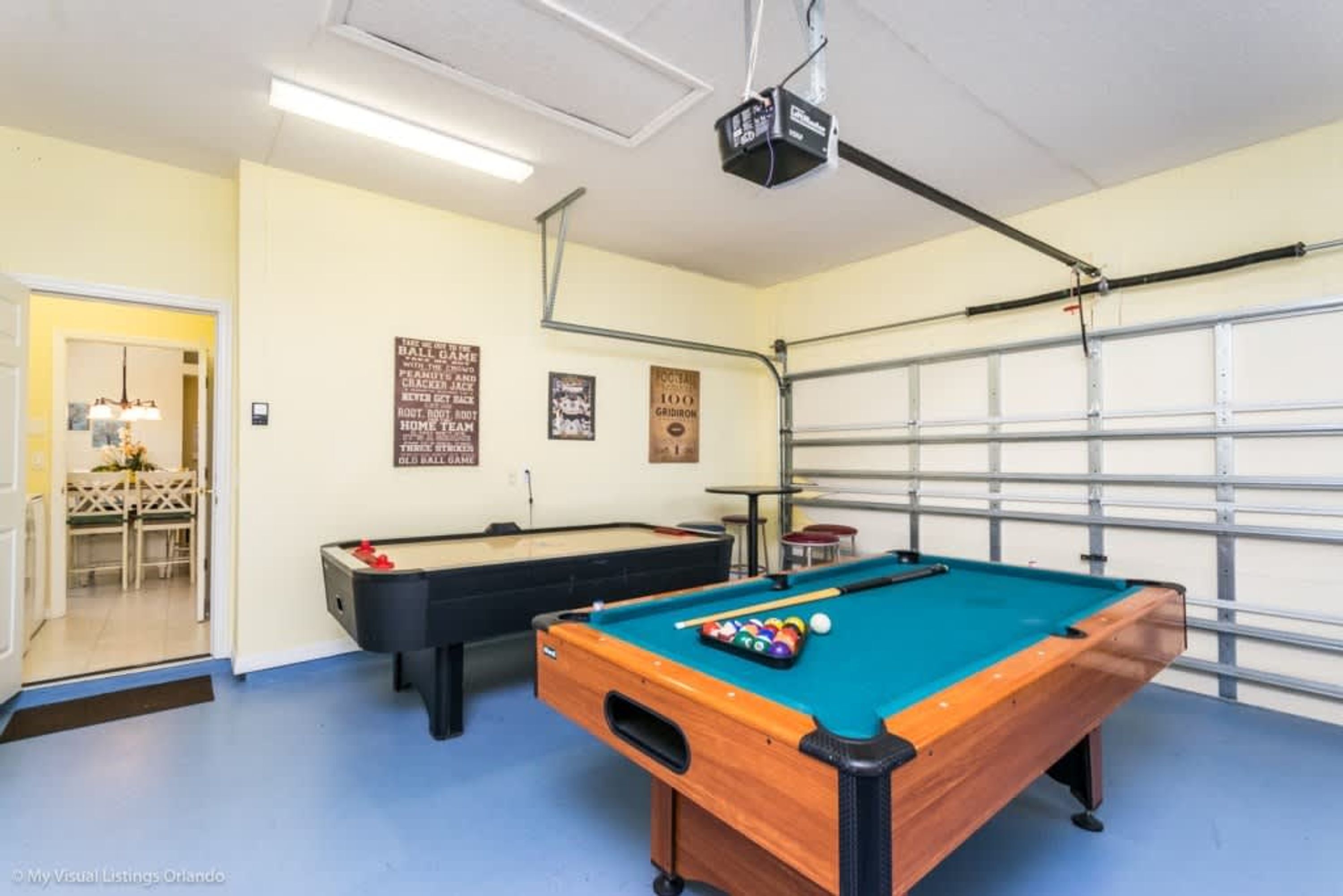 Ett biljardbord med en projektor, ett annat bord längre bak och en garageport.