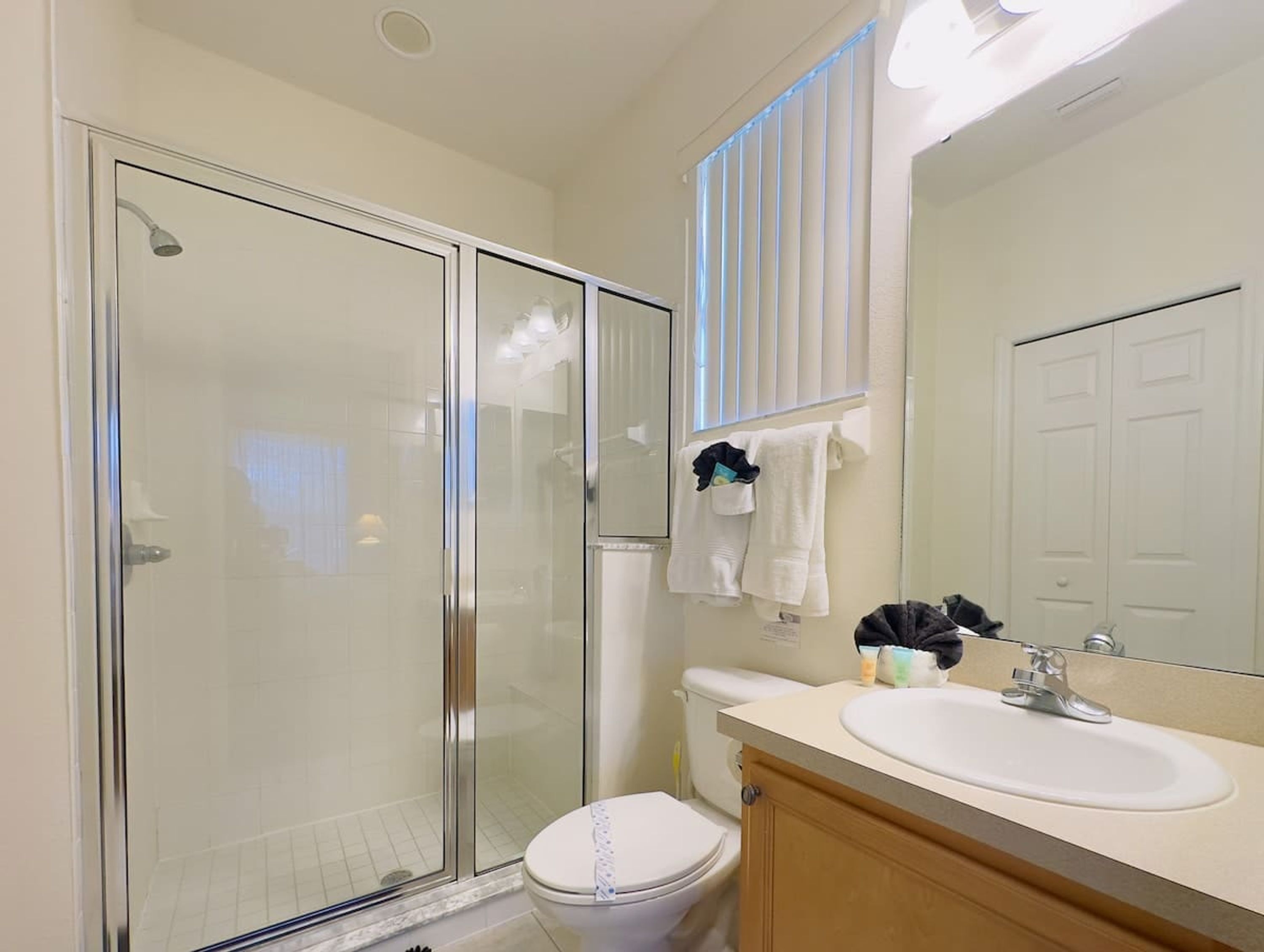Une salle de bain avec une douche à parois de verre, des toilettes, un lavabo avec un miroir au-dessus et un porte-serviettes avec des serviettes.