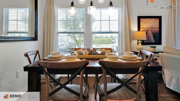 A dining area with a table set for four, a sofa, a TV, and a lamp. - 4BR Charming Oasis With King Beds (Kissimmee)