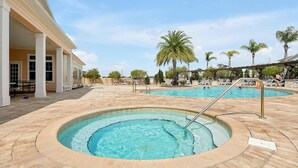 A pool area with a hot tub, palm trees, and a covered seating area. - 4BR Charming Oasis With King Beds (Kissimmee)
