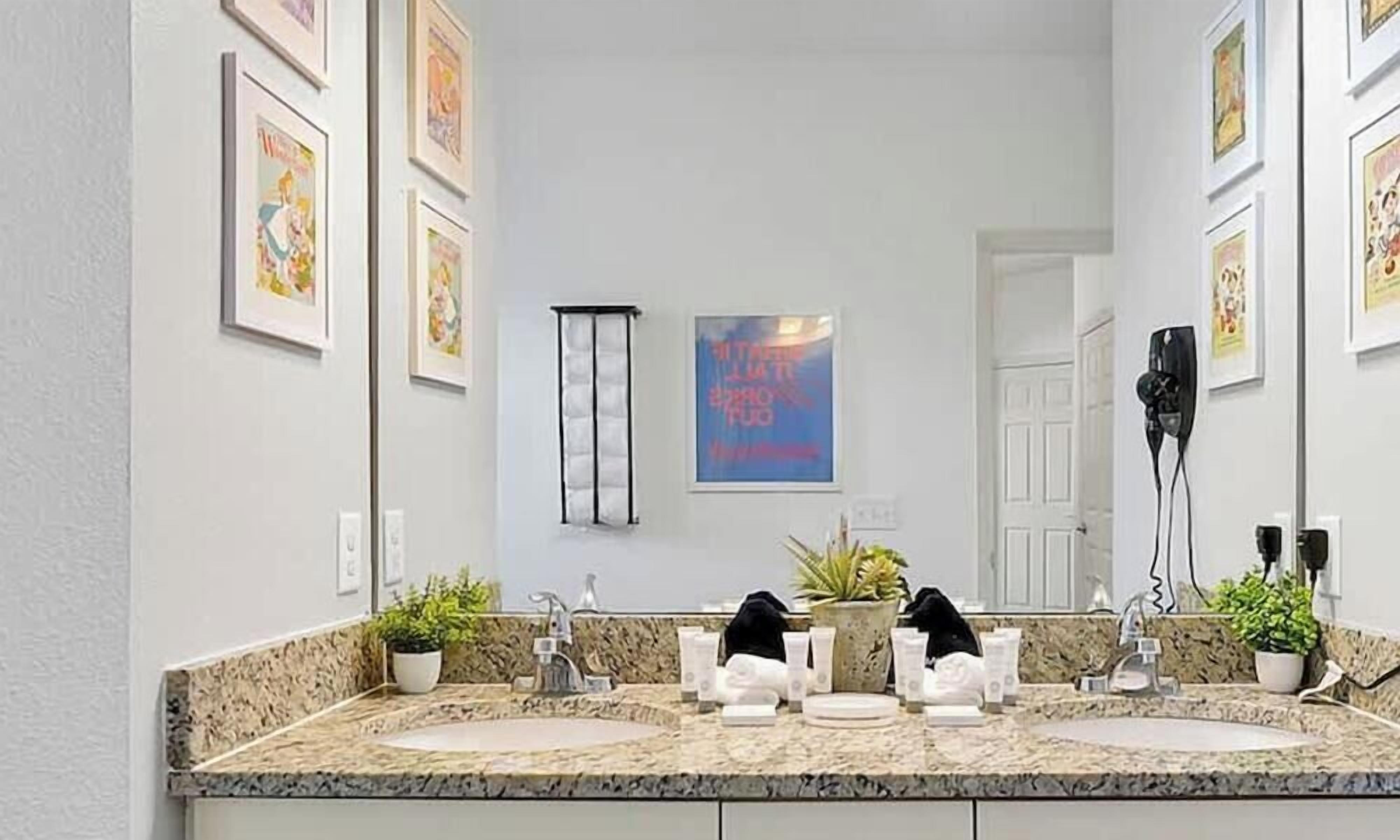 A bathroom with two sinks, a large mirror, and a hairdryer on the wall.