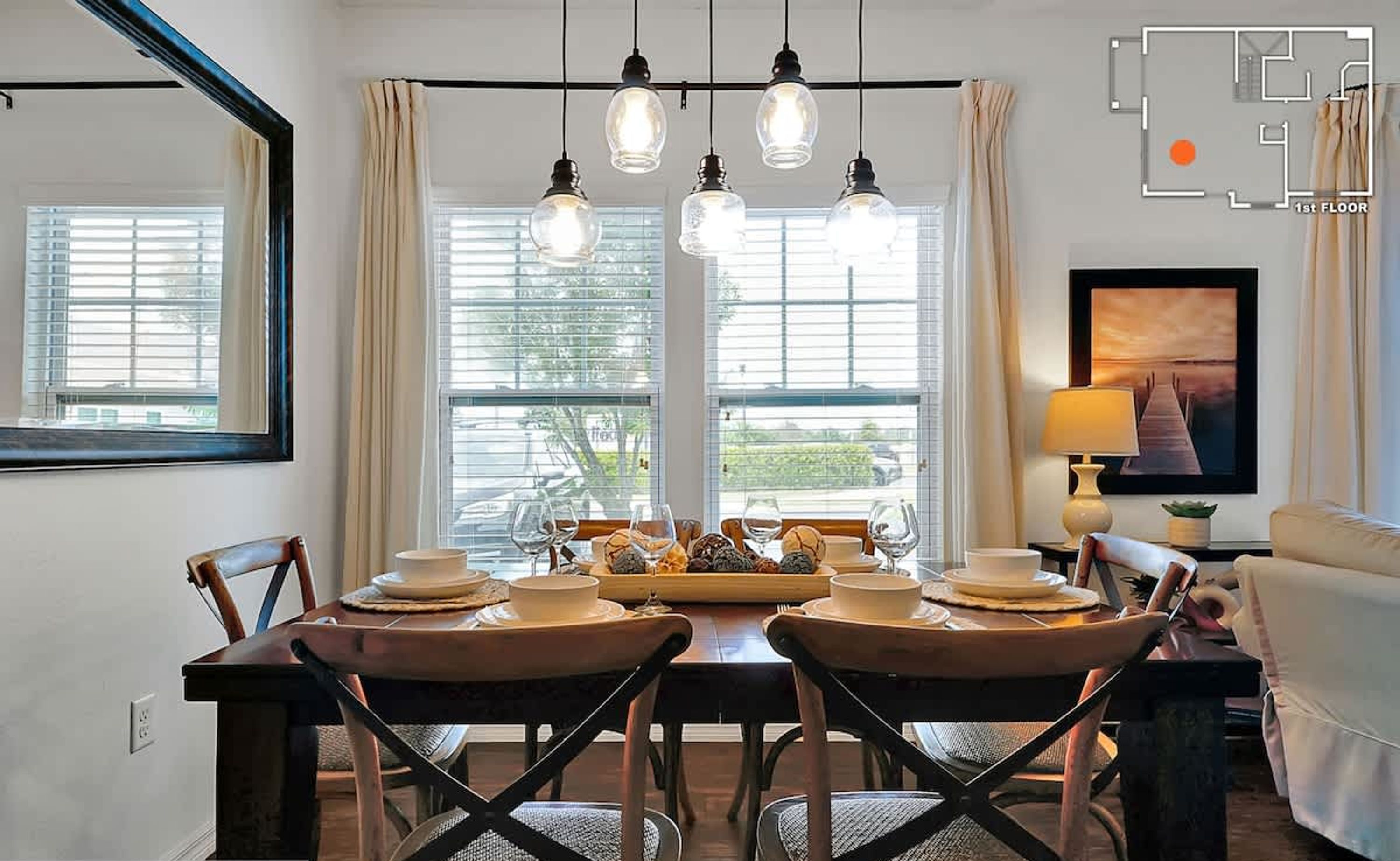 Un coin repas avec une table dressée pour quatre personnes, un canapé, un téléviseur et une lampe.