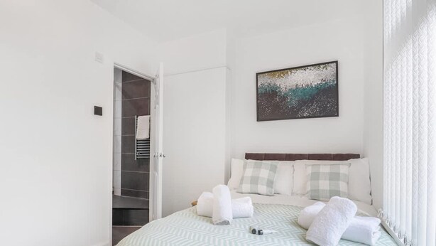A bedroom with a bed, a painting, and a closet. - Charming 2 Bed-ensuites Fast Wi-fi (Coventry)