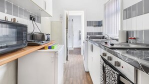 A modern kitchen with a microwave, toaster, and stove. - Charming 2 Bed-ensuites Fast Wi-fi (Coventry)