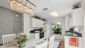 A modern kitchen with white cabinetry, a dining table with chairs, and a chandelier.