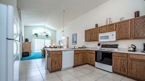 A modern kitchen with wooden cabinets, a white refrigerator, a microwave, and an oven. - Villa Near Disney 4 Bd 3 Bt With Private Pool Quiet Comminuty (Davenport)