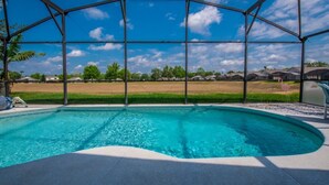A swimming pool with a clear blue water, surrounded by a metal fence, and a view of houses in the background. - Villa Near Disney 4 Bd 3 Bt With Private Pool Quiet Comminuty (Davenport)
