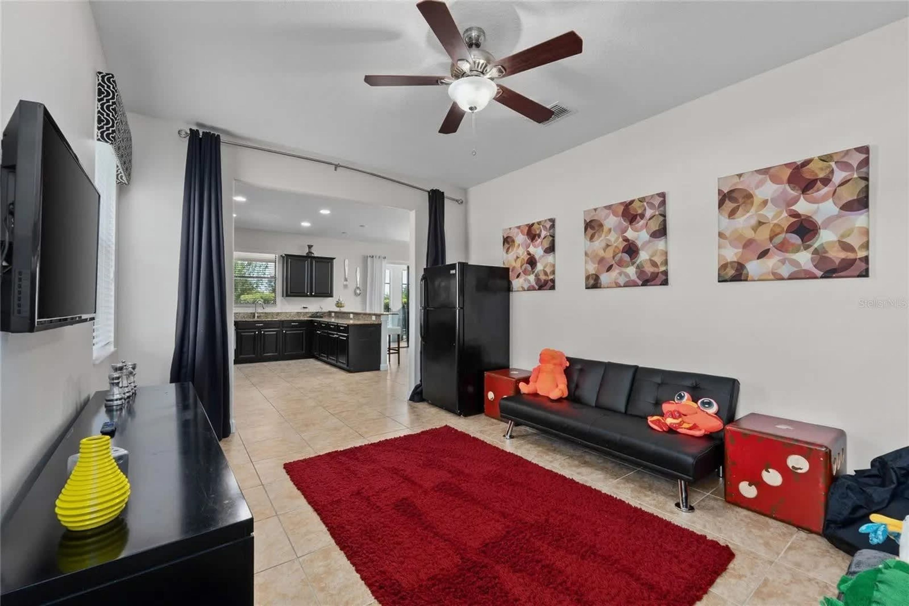 A modern living room with a black sofa, red rug, and artwork on the wall.