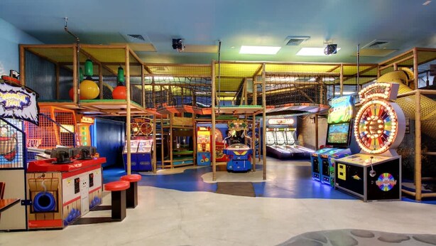 Un área de juegos interior con diversos juegos de arcade, estructuras de escalada y una noria.