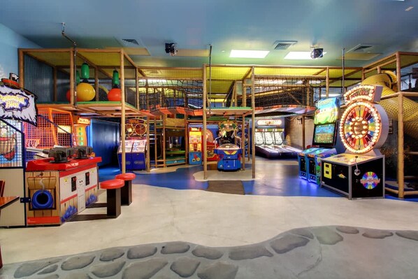 Un área de juegos interior con diversos juegos de arcade, estructuras de escalada y una noria.