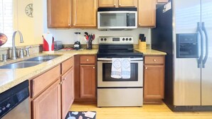 Una cocina con armarios de madera, un refrigerador de acero inoxidable, un microondas, un horno y un lavavajillas.