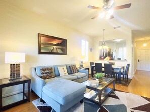 A living room with a sofa, coffee table, and a painting on the wall.