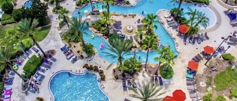A resort with multiple swimming pools, palm trees, and sun loungers.