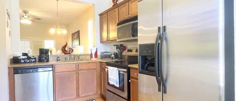 A modern kitchen with stainless steel appliances, wooden cabinets, and a built-in oven.