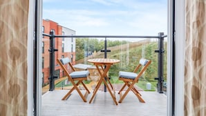 A balcony with a table and four chairs, overlooking a residential area with buildings and greenery. - Harmony 5 Mins to City Centre Balcony Fast Wifi (Coventry)