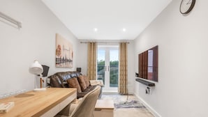 A modern living room with a sofa, a wooden table, a lamp, and a painting on the wall. - Harmony 5 Mins to City Centre Balcony Fast Wifi (Coventry)