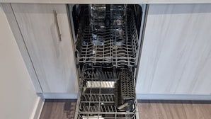 A kitchen with a dishwasher under a white countertop, a stainless steel sink, and a wooden floor. - Harmony 5 Mins to City Centre Balcony Fast Wifi (Coventry)