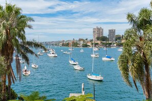 A marina with numerous sailboats docked, surrounded by palm trees and buildings in the background. - Coconut Apartment at Palm View Collective (Sydney)