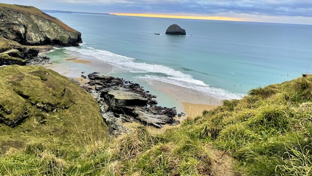 A coastal landscape with a rocky shoreline, a small beach, and a distant view of the sea under a cloudy sky. - The Mermaid Loft in Cornwall (Tintagel)