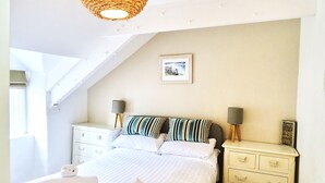 A bedroom with a bed, two bedside tables with lamps, a window, and a picture on the wall. - The Mermaid Loft in Cornwall (Tintagel)