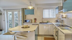 A modern kitchen with a central island, a microwave, a sink, and a stove. - The Mermaid Loft in Cornwall (Tintagel)