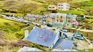 A coastal village with traditional stone houses, a main road, and a parking area. - The Mermaid Loft in Cornwall (Tintagel)