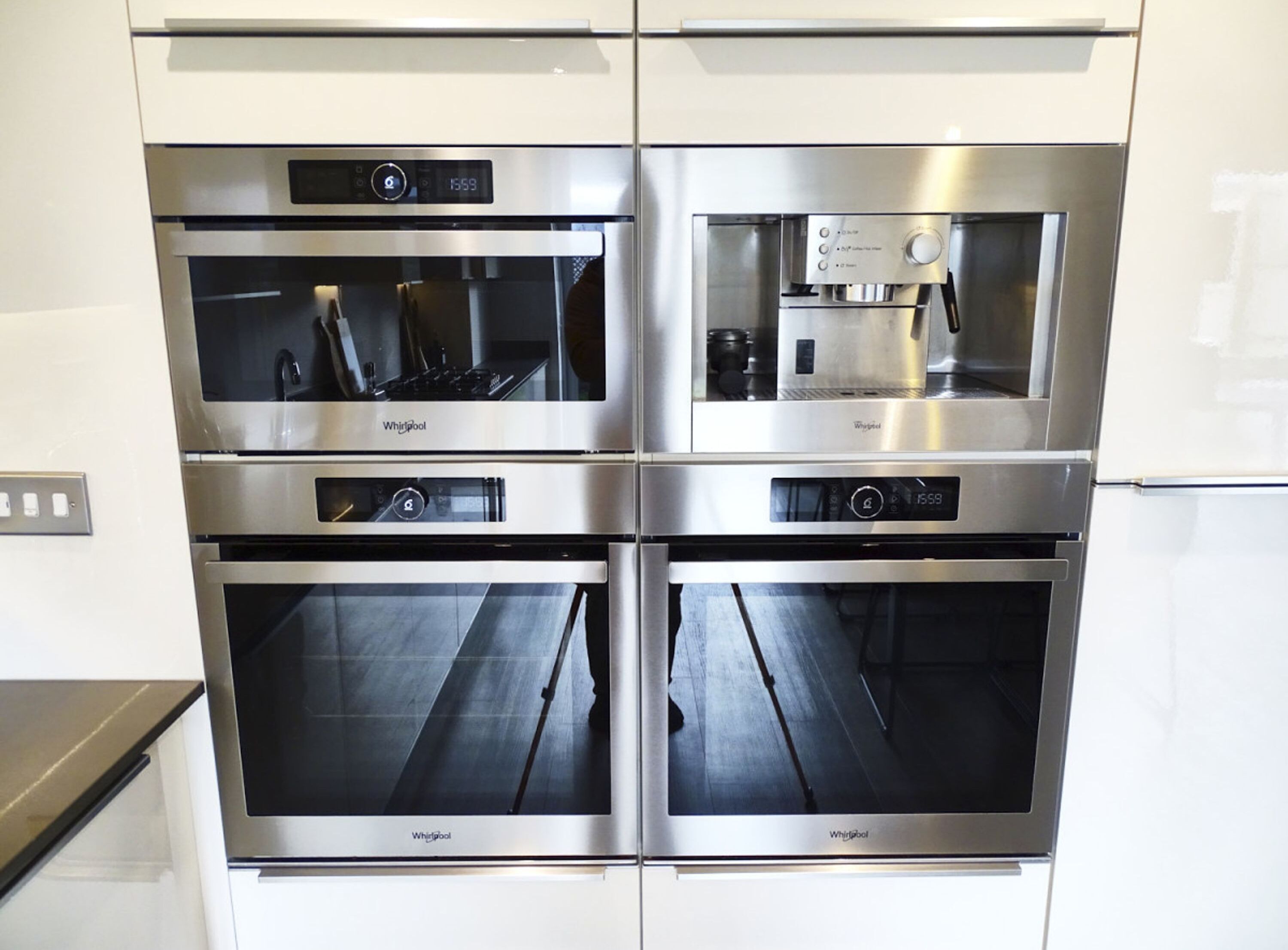 Een keuken met vier roestvrijstalen Whirlpool ovens, een ingebouwde koffiezetapparaat en een koelkast.