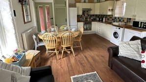 A compact living space with a dining area, kitchen, and seating area. - The Stables in Crackington Haven (Bude)