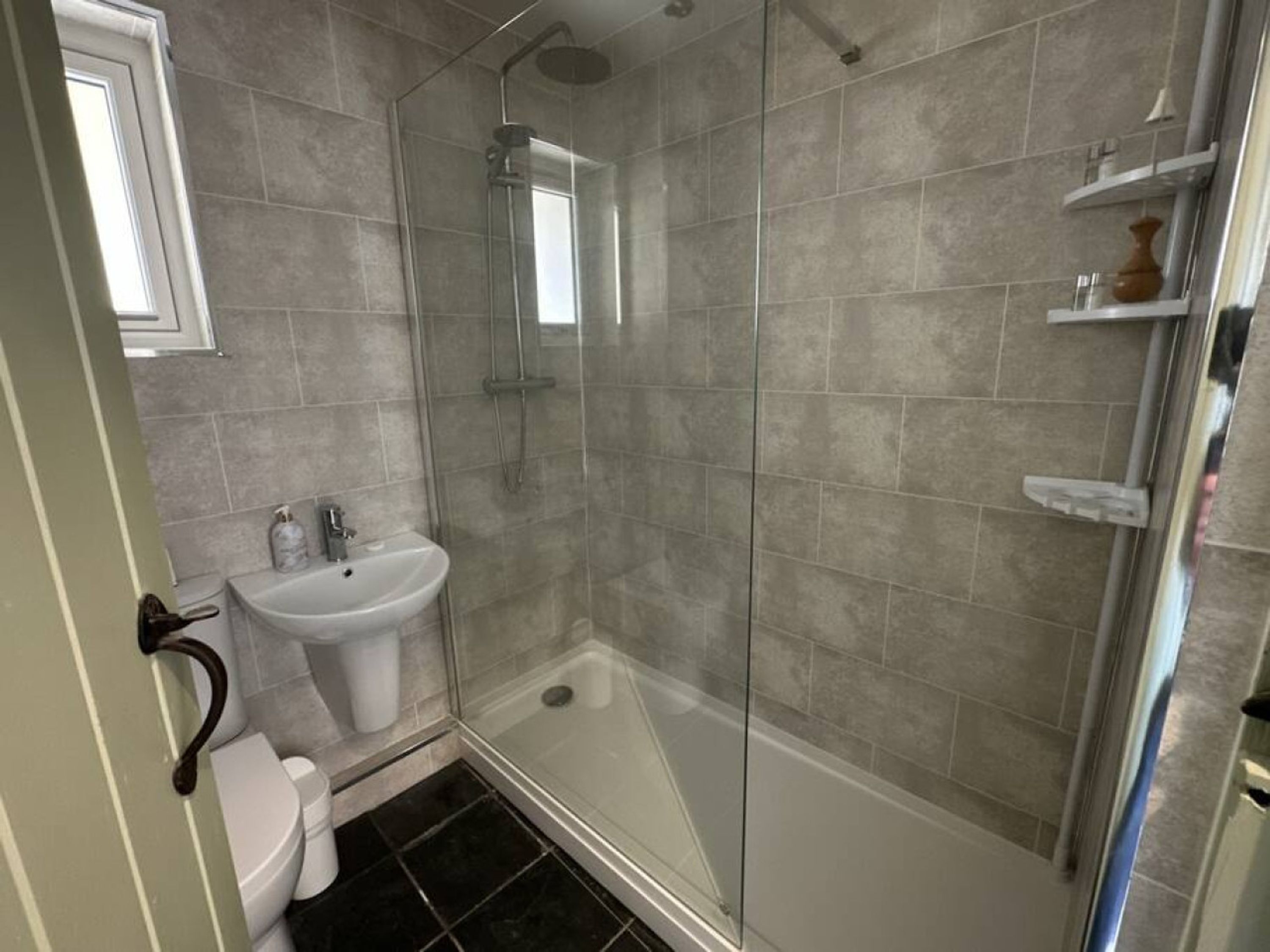A bathroom with a glass-enclosed shower, a white sink, and a toilet.